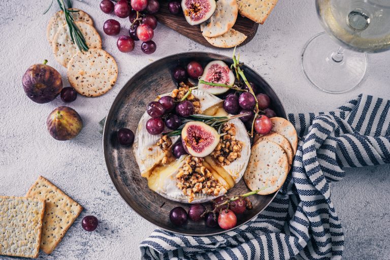 Baked Brie with Walnuts & Fresh Fig on a plate with a napkin and glass of white wine